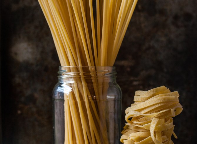 Una collezione di pasta in barattoli con sopra diversi tipi di pasta.