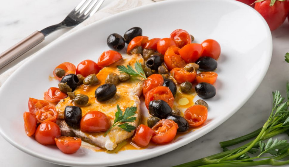 Pesce spada alle olive e all'aceto balsamico su piatto bianco con forchetta